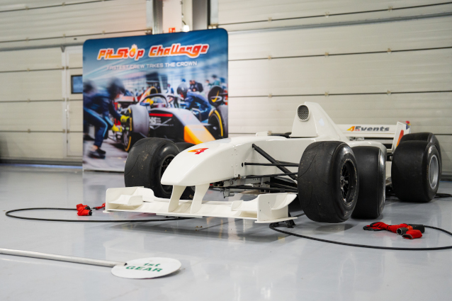 A white formula one race car model in front a display sign labelled Pit Stop Challenge.
