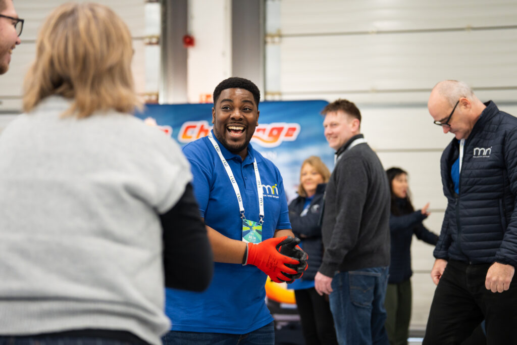 A man wearing a blue shirt and smiling at an event.